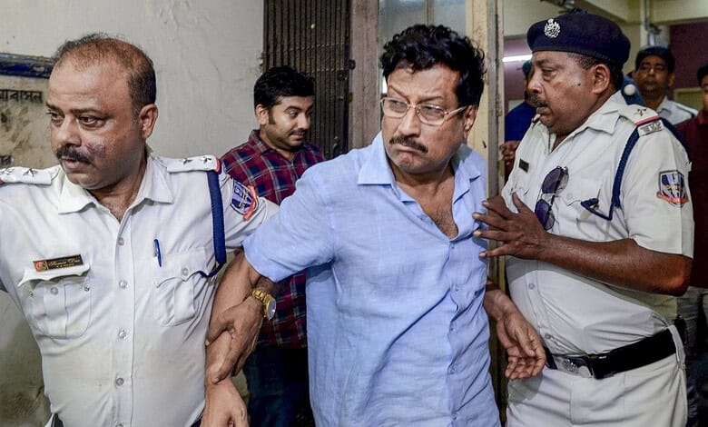 A man in a blue shirt being escorted by police officers outside a building.