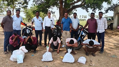 Group of men with motorcycles participating in a community cleanup event outdoors in a rural area.