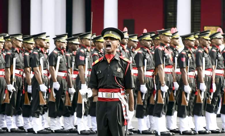 A soldier leading a military parade with uniformed personnel standing in formation behind him.