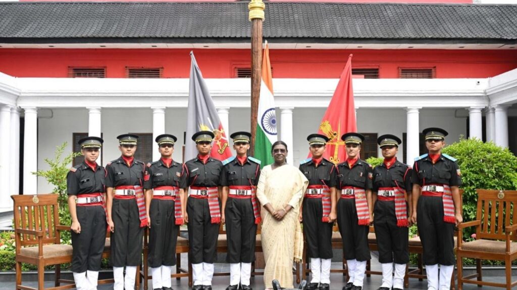 A woman in traditional attire standing with uniformed officers in front of a government building with Ind.