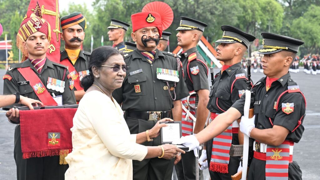 A woman in white presenting an award to a uniformed soldier during a military ceremony.