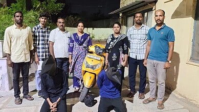 Group of eight people standing outdoors with a yellow scooter in front, sunny day, casual attire, diverse.