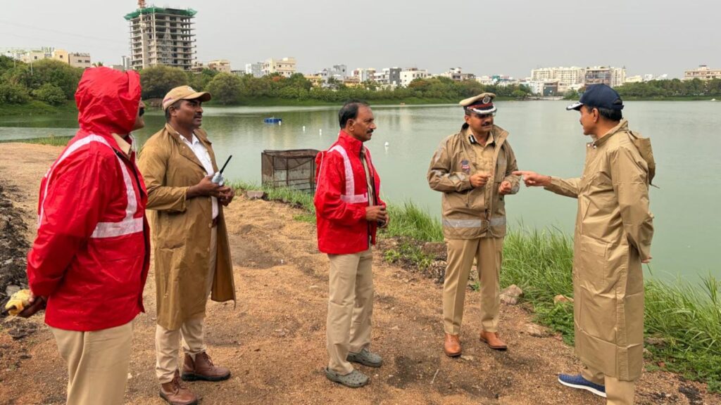 Officials and environmental experts discuss water quality near a riverbank in an urban area.