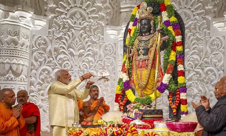 A Hindu priest performing a ritual in front of a decorated black stone deity statue adorned with flowers.