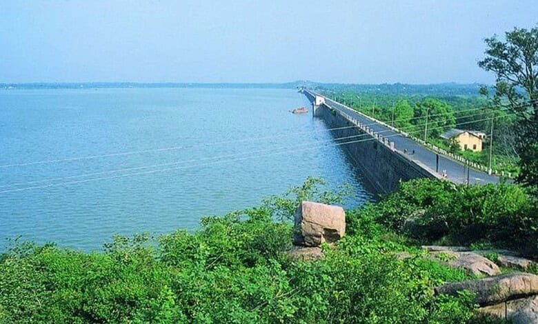Serene view of a long bridge over a calm water body with lush greenery and clear blue sky in the backgrou.