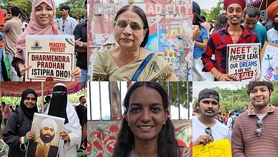 A woman protesting peacefully at a rally with a sign about Dharmendra Pradhan.