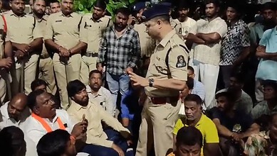A police officer addressing a group of men outdoors, some seated and some standing, in a community settin.