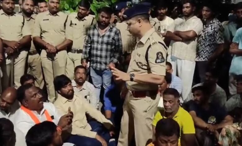 A police officer addressing a group of men outdoors, some seated and some standing, in a community settin.