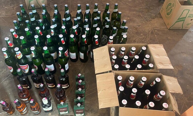 Bottles of alcohol arranged in a semi-circle with some in cardboard boxes on the ground.