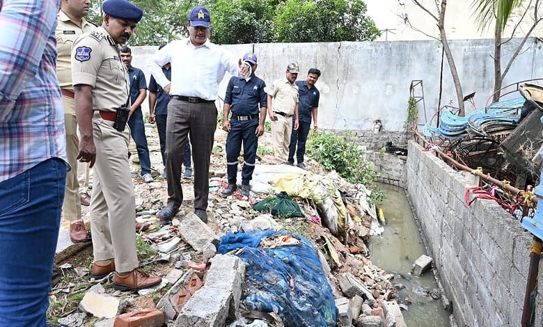 Officials inspecting a drainage area filled with debris and garbage after monsoon rains.