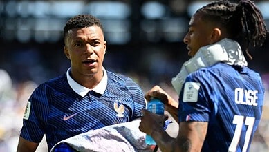 French football players during a match, one holding a water bottle, in blue jerseys.