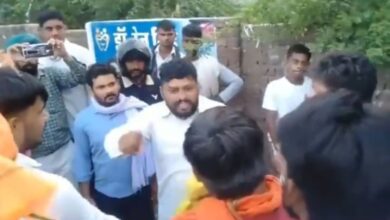 Group of men gathered outdoors, one man speaking passionately to others.