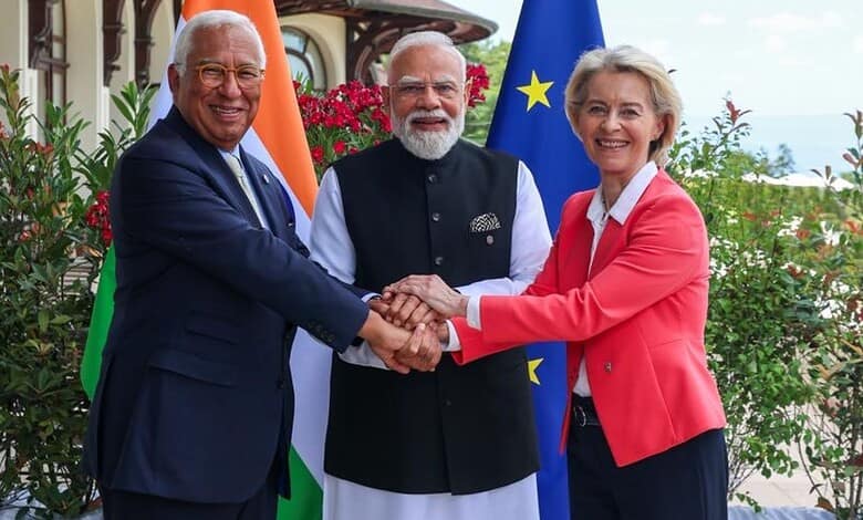 Indian Prime Minister Narendra Modi, European Union leader, and Indian official shake hands outdoors.
