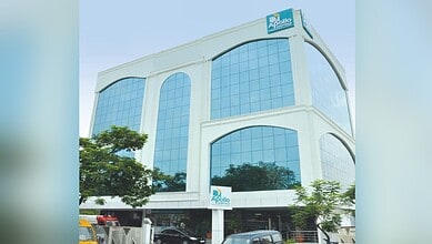 Modern Apollo Hospitals building with glass facade and greenery in front.
