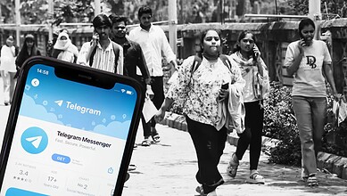 Students walking outdoors with a smartphone displaying Telegram app in the foreground.