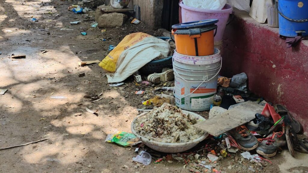 Rough street scene with scattered trash, shoes, and buckets in Hyderabad.