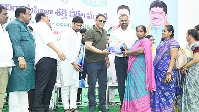 Mohammed Azhruddin hands over a saree to a woman at a programme in Hyderabad