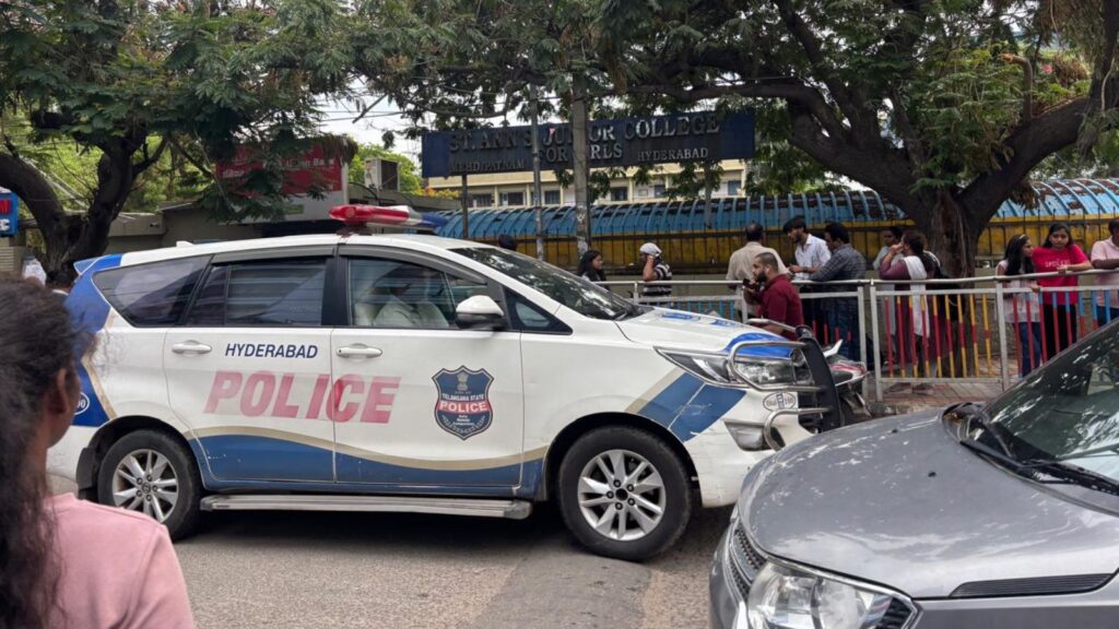 Police car parked outside an educational institution during a busy day.
