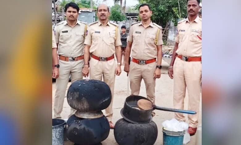Police officers standing behind seized illegal alcohol bottles in Telangana.