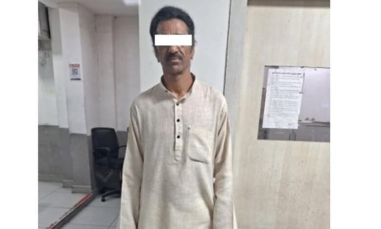 Man in beige kurta with white background, detained by police in Hyderabad.