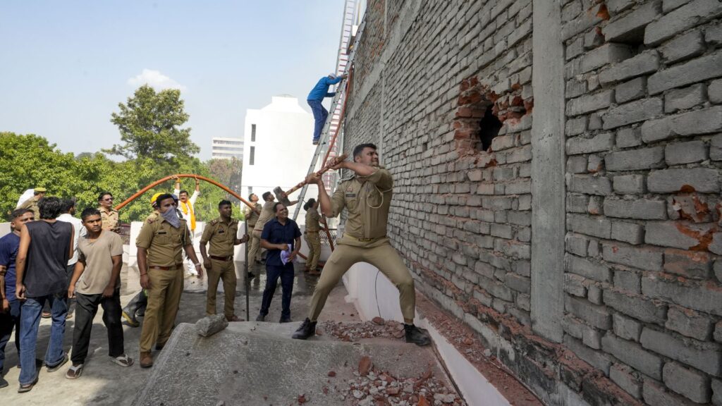Police officer breaks wall with a sledgehammer during a protest or demonstration.