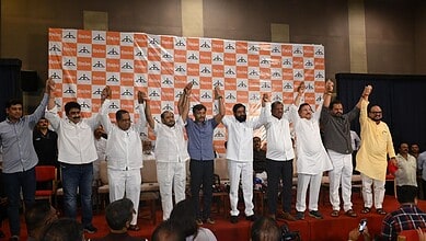 Political leaders on stage celebrating with raised hands at a public event.