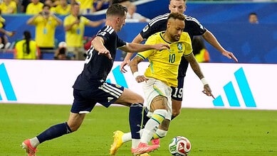 Brazilian player Neymar dribbling the ball past Scottish defenders during a FIFA World Cup match.