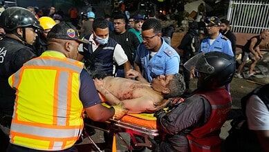 Rescue workers assist a man injured in the Venezuela earthquake at night.