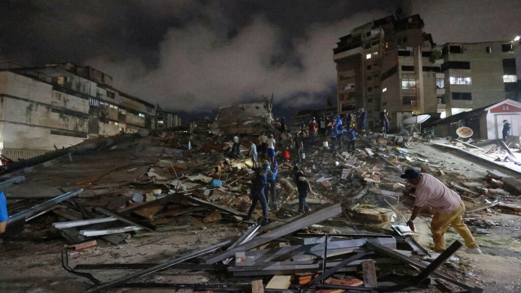 Rescue workers search through debris after Venezuela earthquake at night.