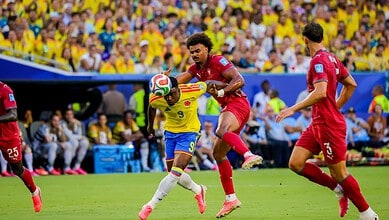 Colombian and Portuguese football players compete for the ball during a match.