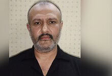 Close-up of a middle-aged man with a beard and short hair, wearing a black shirt.