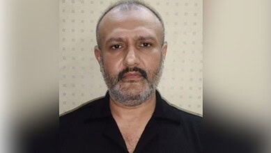 Close-up of a middle-aged man with a beard and short hair, wearing a black shirt.