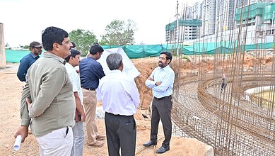 Construction site with officials discussing water infrastructure development in Hyderabad.