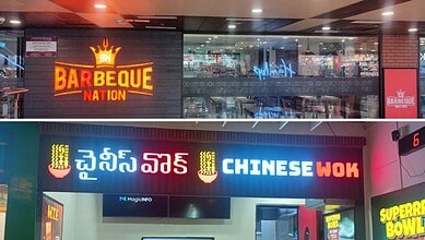 Bright neon signs for Barbeque Nation and Chinese Wok restaurant in a shopping mall.