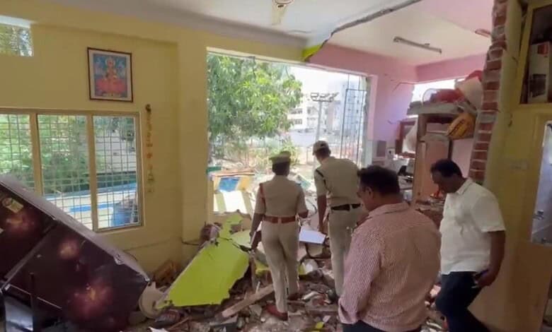 Interior of a house damaged by an explosion, with debris and police officers inspecting the scene.