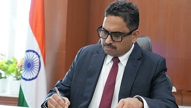 Sanjay Jaju in formal attire during a meeting with Indian flag in the background.