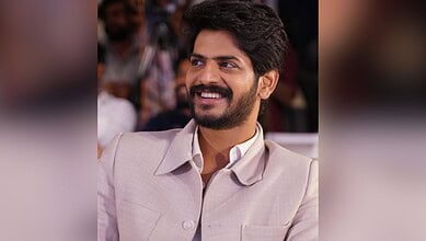 Actor Akhil smiling in a beige suit at a public event.