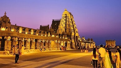 Yadagirigutta temple illuminated at dusk with visitors in the foreground.