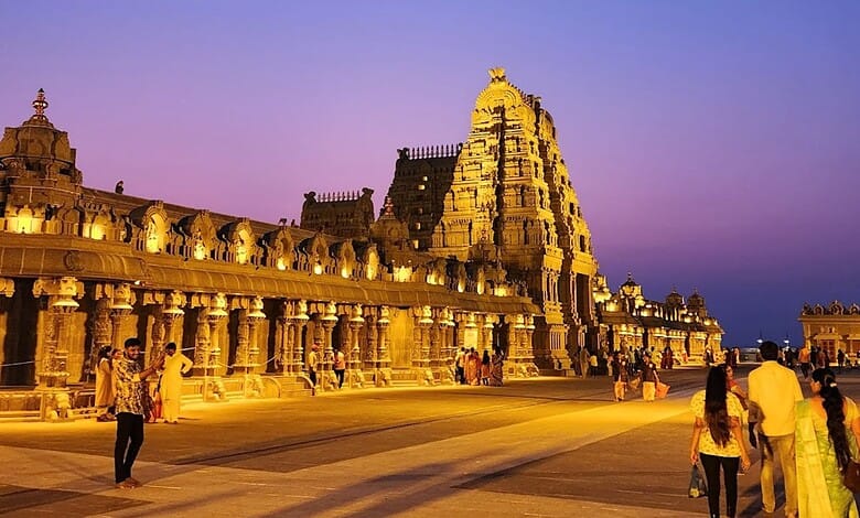 Yadagirigutta temple illuminated at dusk with visitors in the foreground.