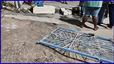 Collapsed blue metal gate on the ground after compound wall collapse in Bengaluru.