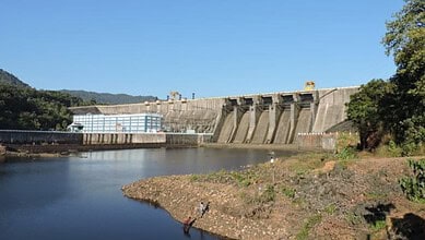 Sharavathi hydel plant dam with water reservoir and surrounding greenery under clear blue sky.