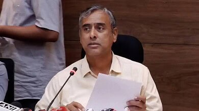 Official at a press conference holding a paper, speaking into a microphone.