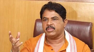 Karnataka CM in orange shirt speaking passionately during a press conference.