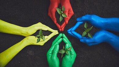 Protecting the environment with colourful hands holding small green plants for sustainability and eco-fri.