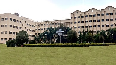 Large government or institutional building with a well-maintained lawn and palm trees in front.