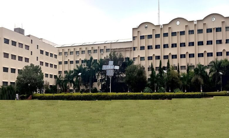 Large government or institutional building with a well-maintained lawn and palm trees in front.