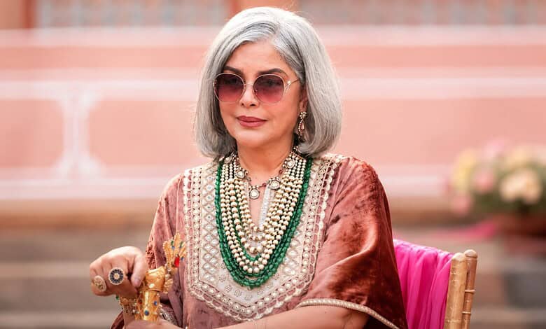Zeenat Aman with silver hair, sunglasses, and traditional jewelry at an event.