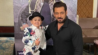 A young boy and a man posing together at an indoor event, smiling and dressed in stylish attire.