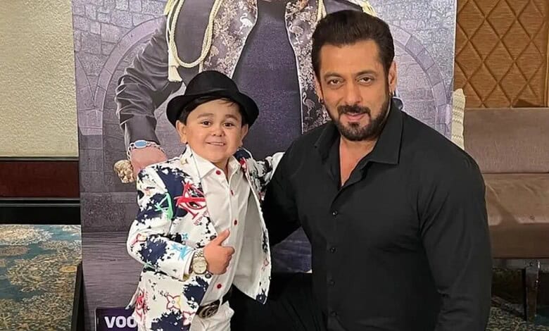 A young boy and a man posing together at an indoor event, smiling and dressed in stylish attire.