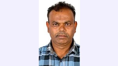 Man in a checkered shirt with a serious expression, facing the camera.